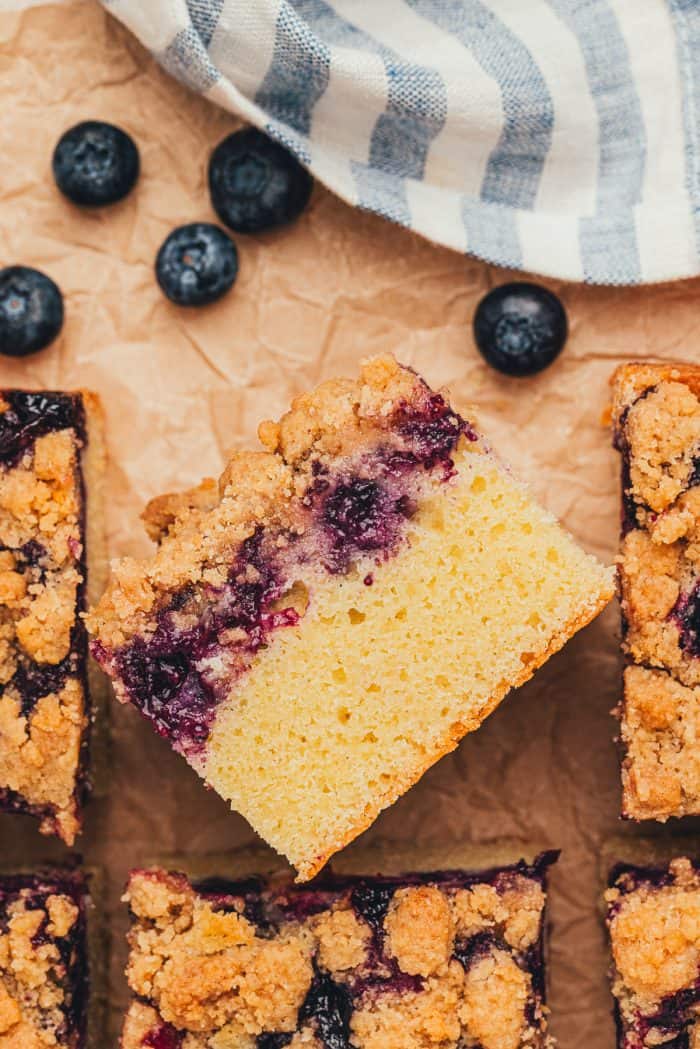A slice of blueberry crumb cake turned over on its side with more slices around it.