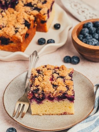 Two blueberry crumb cake slices on small plates.