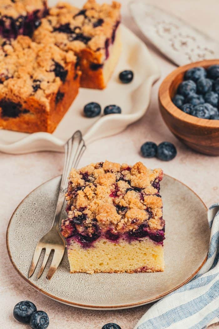 Two blueberry crumb cake slices on small plates.
