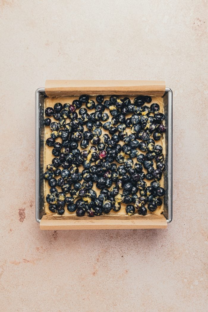 The cake batter and blueberry mixture in a prepared cake pan.