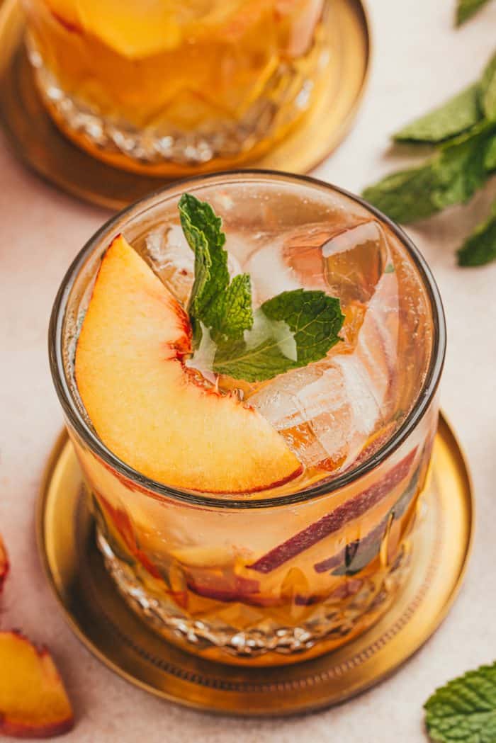 An upclose of a peach bourbon smash.