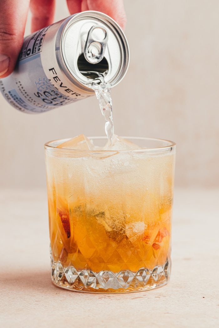 Topping the drink off with club soda.