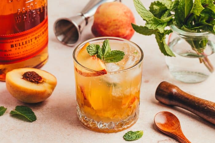 An upclose of a peach bourbon smash.