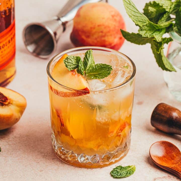 An upclose of a peach bourbon smash.