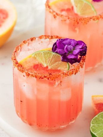 Two Guava Paloma in glasses with flower garnishes.