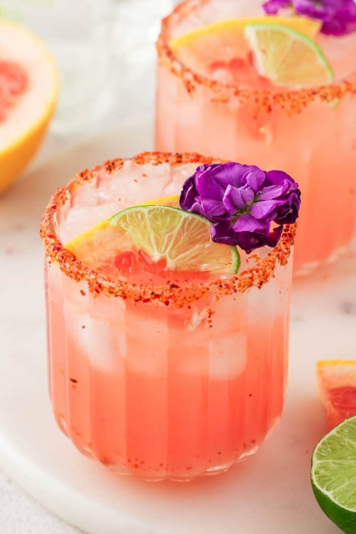 Two Guava Paloma in glasses with flower garnishes.
