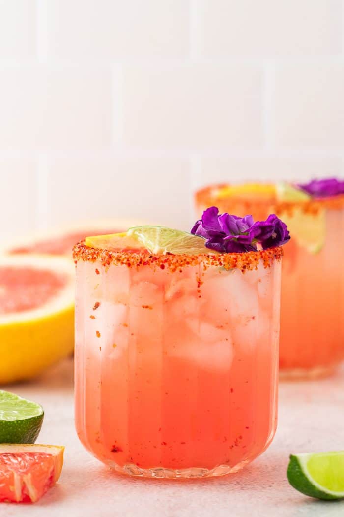 Two Guava Paloma in glasses with flower garnishes.