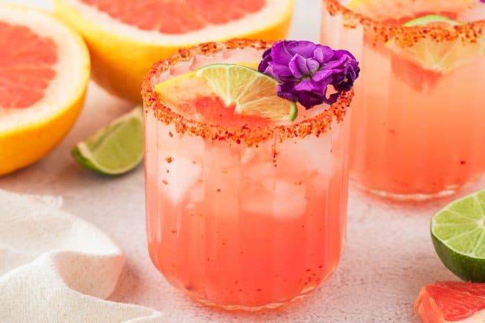 Two Guava Paloma in glasses with flower garnishes.