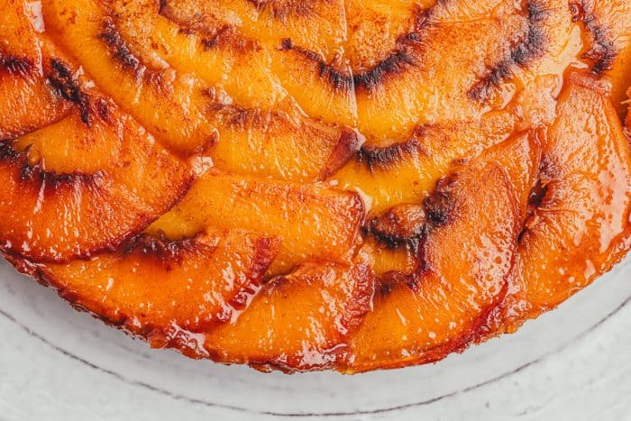 An upclose view of the sliced peaches on an upside-down peach cake.