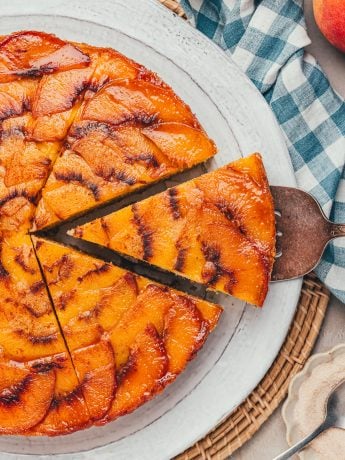A slice of peach upside down cake being removed from the whole cake.