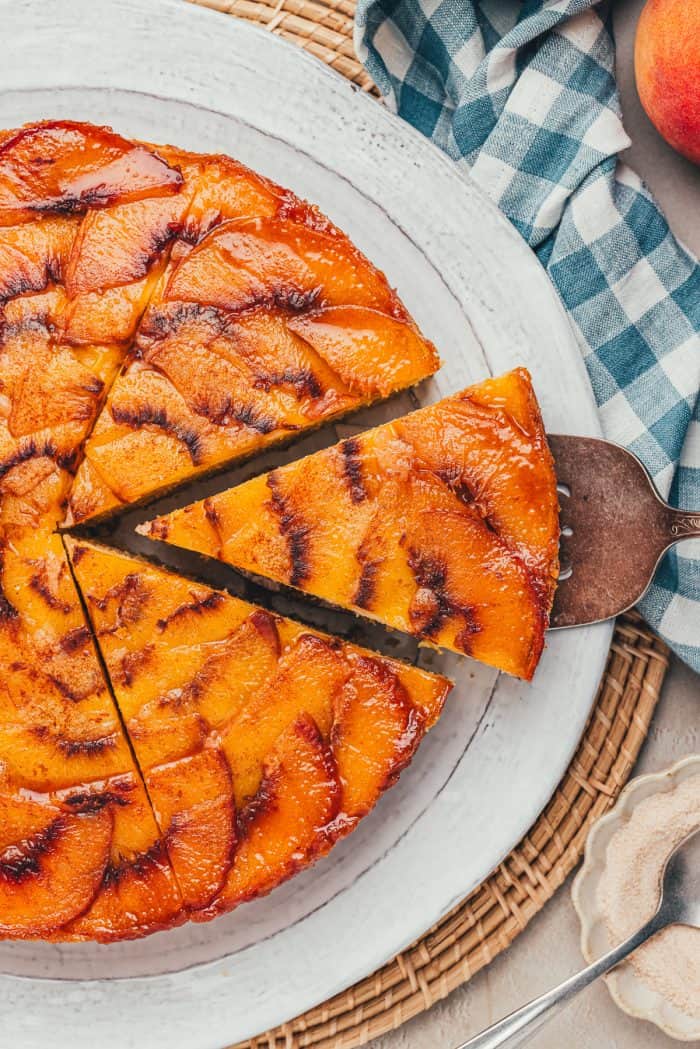 A slice of peach upside down cake being removed from the whole cake.