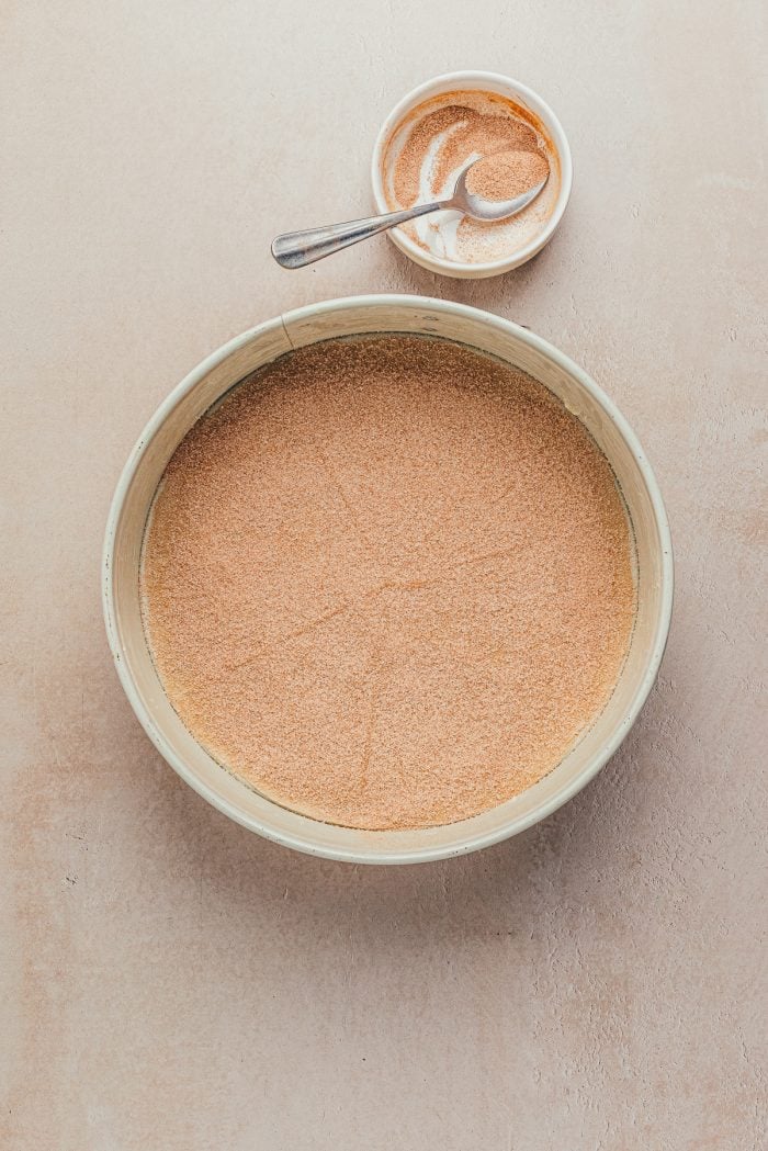 A round cake pan with cinnamon sugar sprinkled on the bottom.