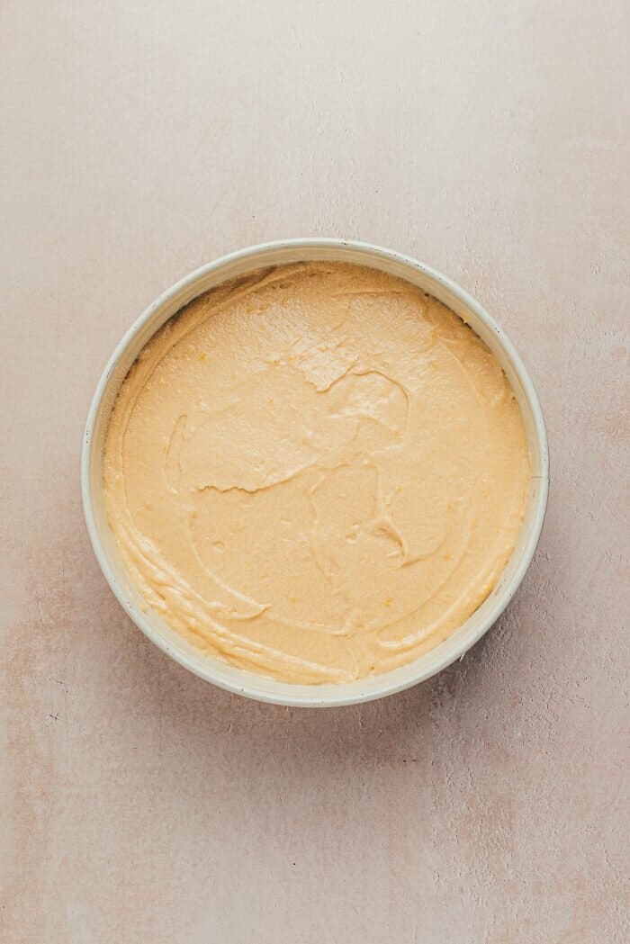 A round cake pan with cake batter in it.
