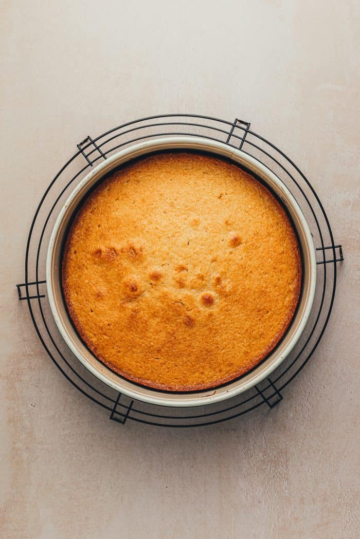 A round cake pan with a baked upside-down peach cake on a cooling rack.