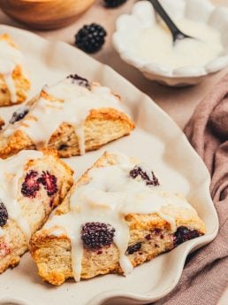 Glazed blackberry scones on a platter.