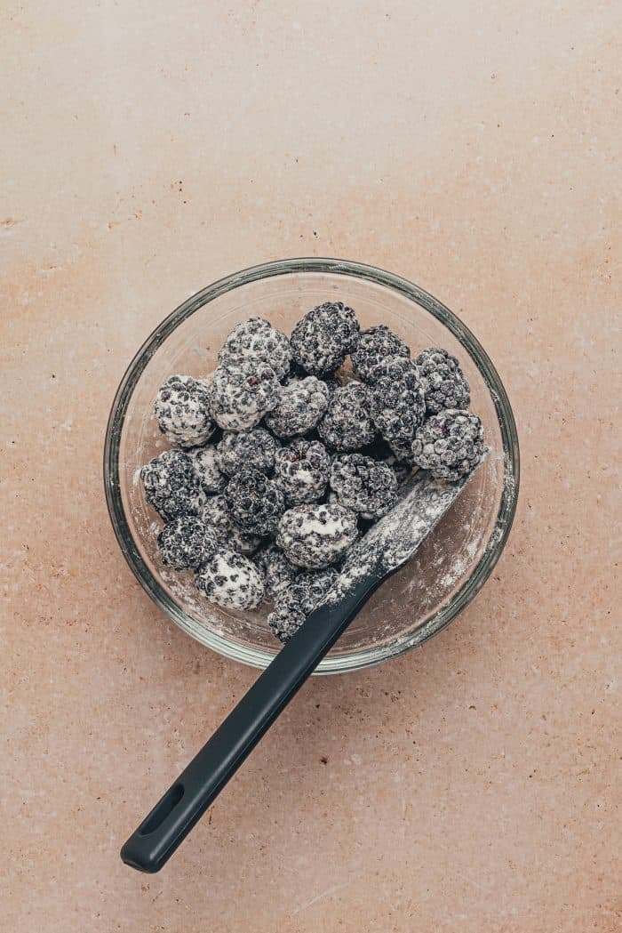 A glass bowl with fresh blackberries tossed in flour.