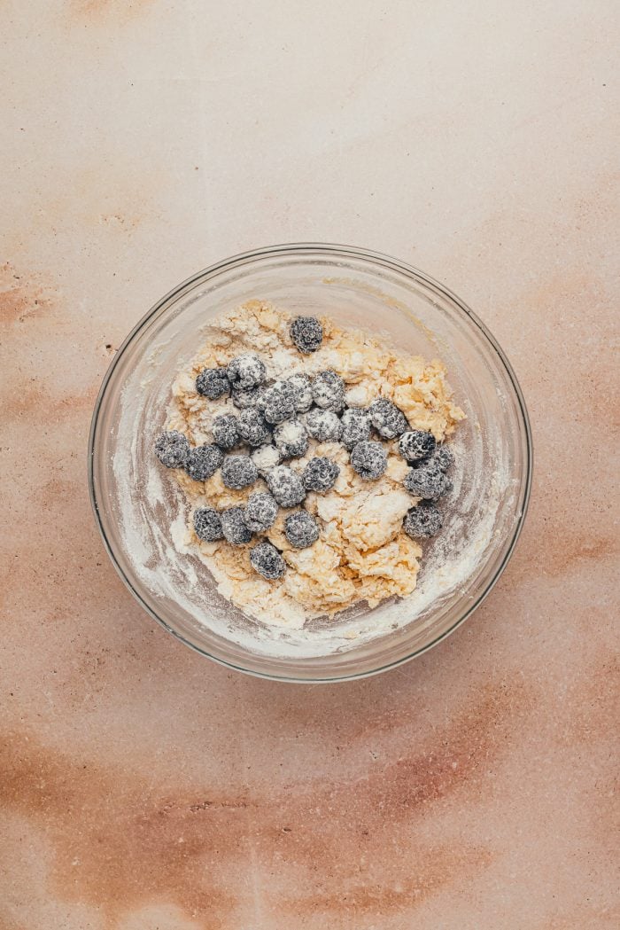 The scone dough with the blackberries added in a glass bowl.