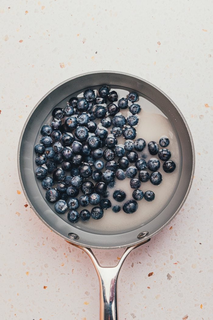 A saucepan with fresh blueberries and sugar.