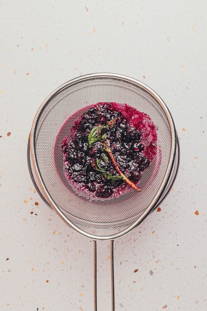 The homemade blueberry syrup being strained.