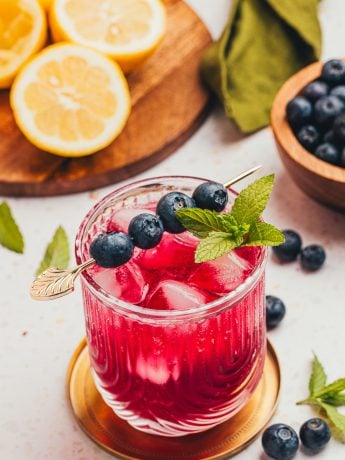 A blueberry gin fizz cocktail garnished with blueberries and mint.