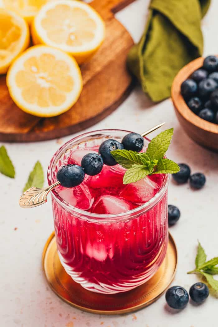 A blueberry gin fizz cocktail garnished with blueberries and mint.