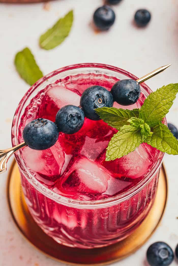 A blueberry gin fizz cocktail garnished with blueberries and mint.