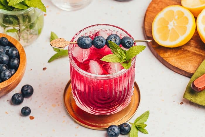 A glass filled with a blueberry gin fizz.