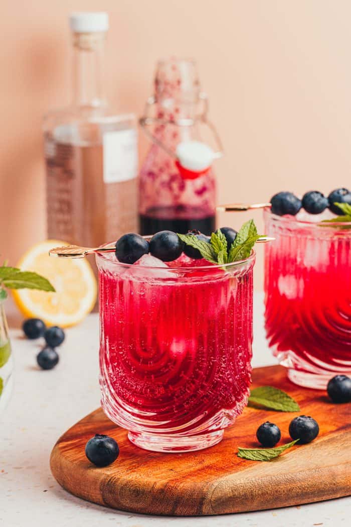 A blueberry gin fizz cocktail garnished with blueberries and mint.
