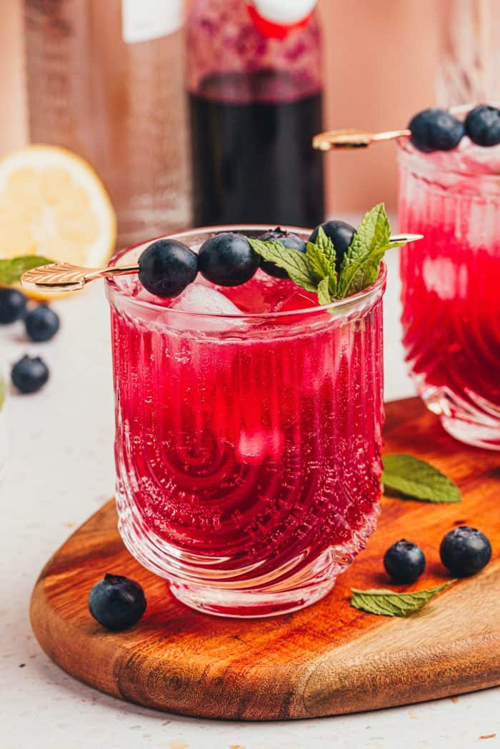 A blueberry gin fizz cocktail garnished with blueberries and mint.