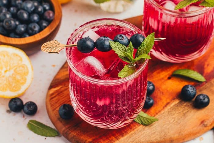 Two glasses filled with  blueberry gin fizzes.