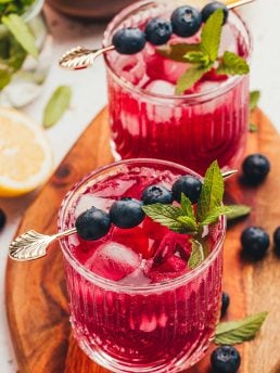 A blueberry gin fizz cocktail garnished with blueberries and mint.