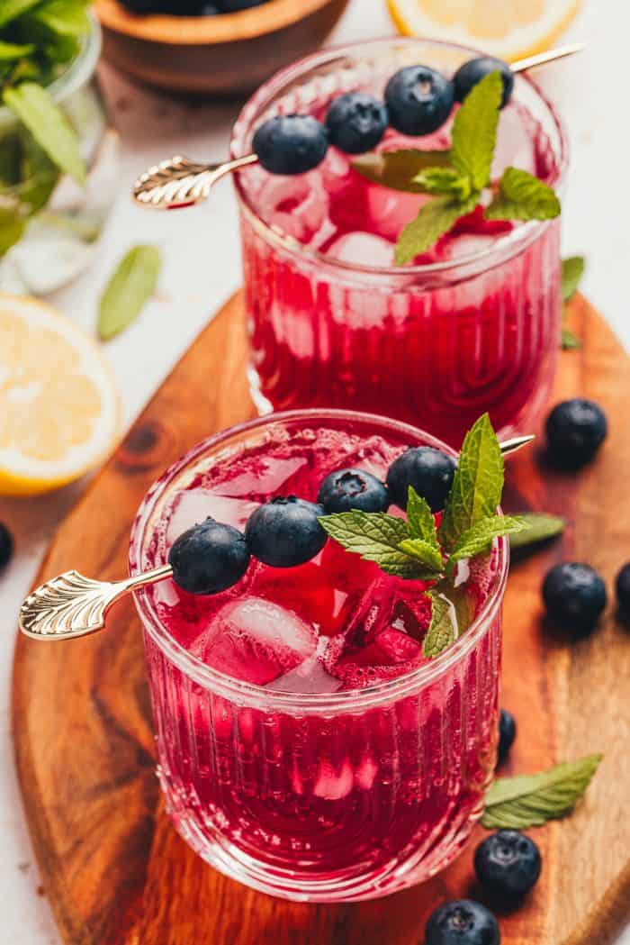 A blueberry gin fizz cocktail garnished with blueberries and mint.