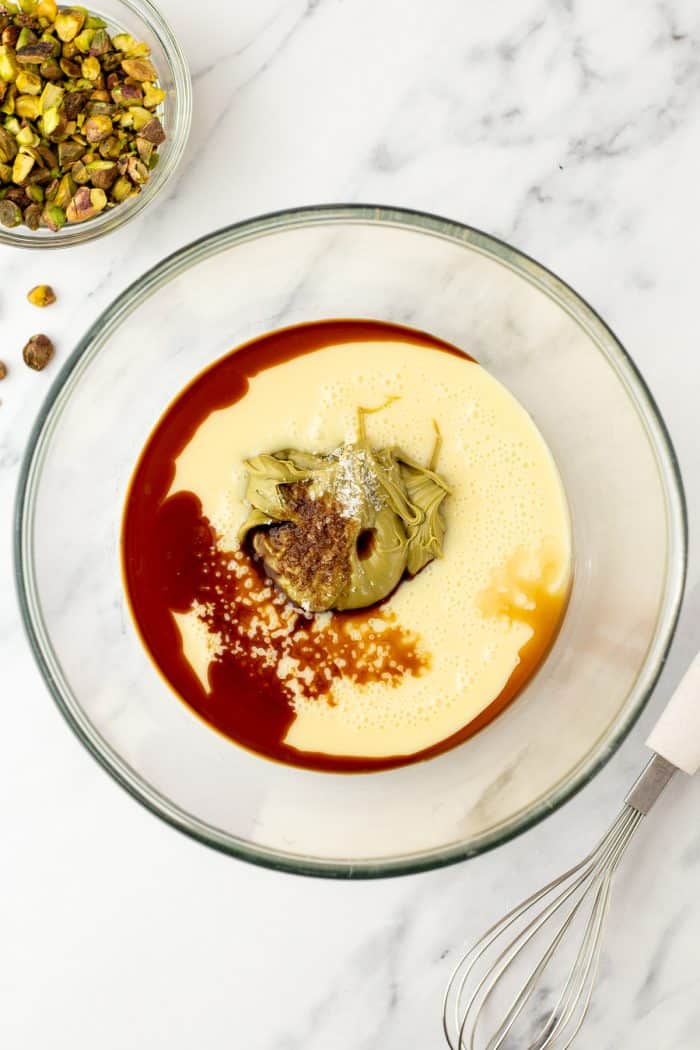 A glass mixing bowl with condensed milk and vanilla extract.