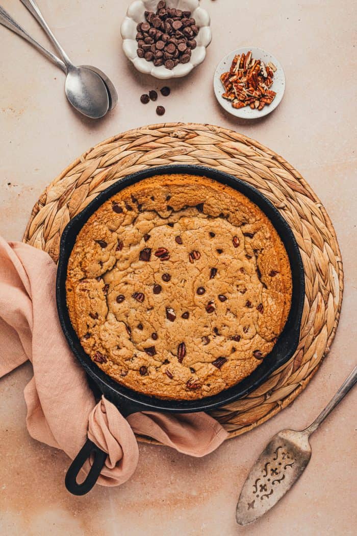 A baked chocolate chip cookie skillet on a placemat with a napkin.
