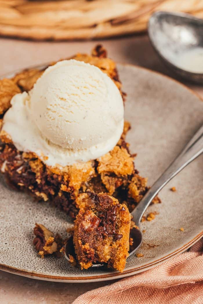 A plate with a slice of brown butter pecan chocolate chip skillet cookie.