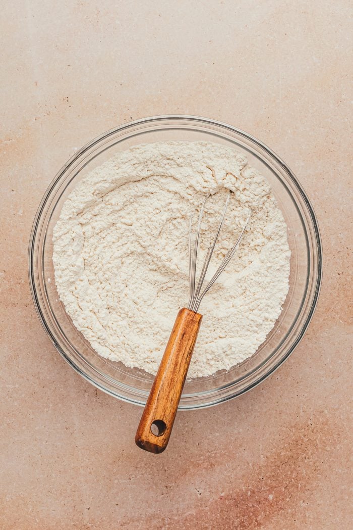 The dry ingredients in a glass bowl with a whisk.