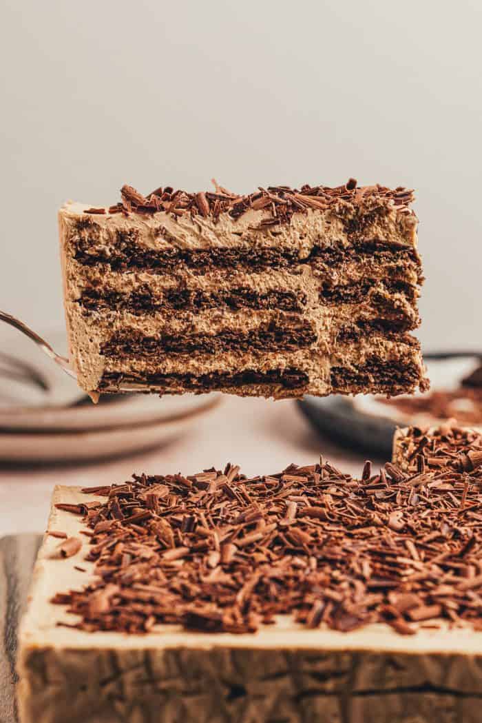 A slice of the chocolate icebox cake on a spatula being lifted in the air.