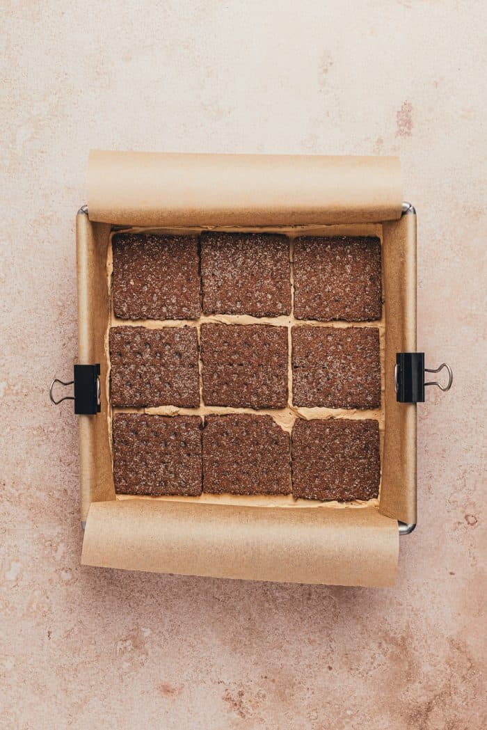 Graham crackers spread over espresso cream in a square pan.