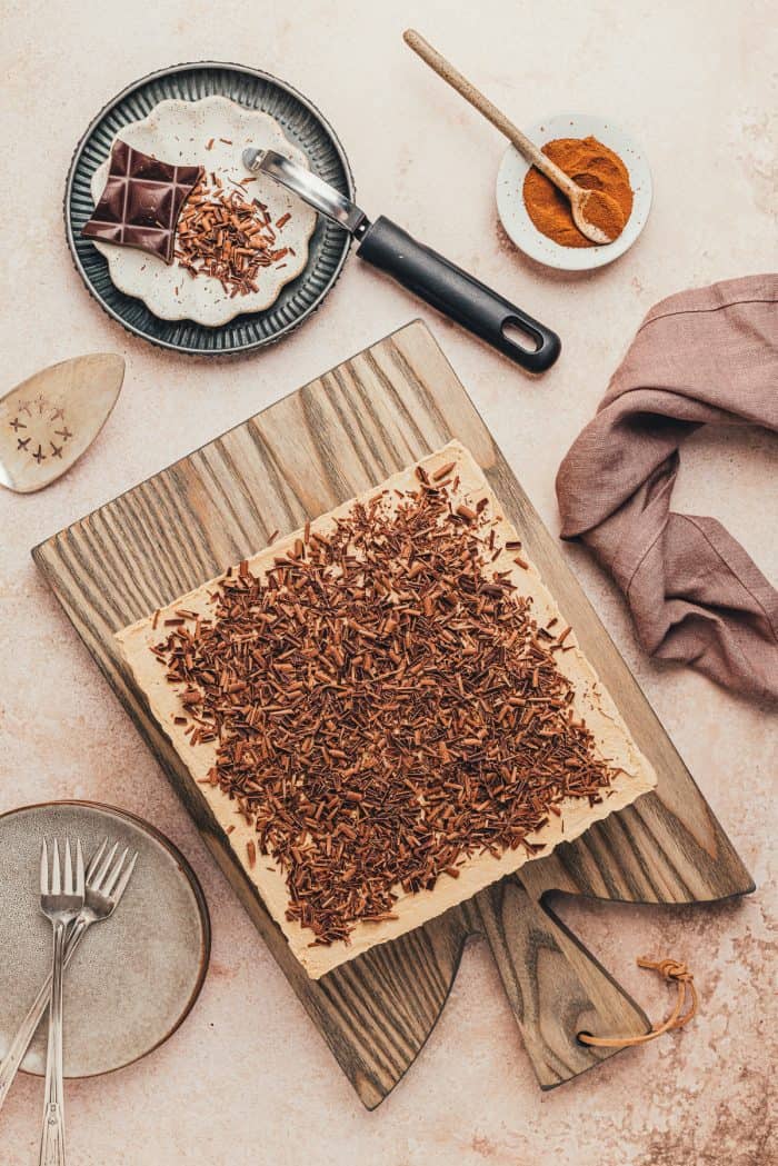A cutting board with chocolate espresso icebox cake and a knife in the background.