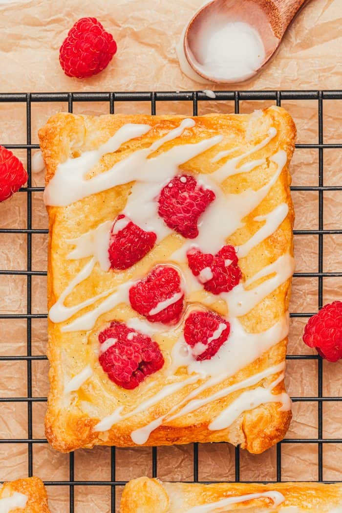 A freshly baked raspberry cream cheese danish on a cooling rack.