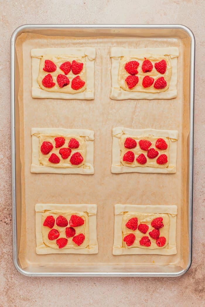 Fresh raspberries topped over unbaked cream cheese danishes.