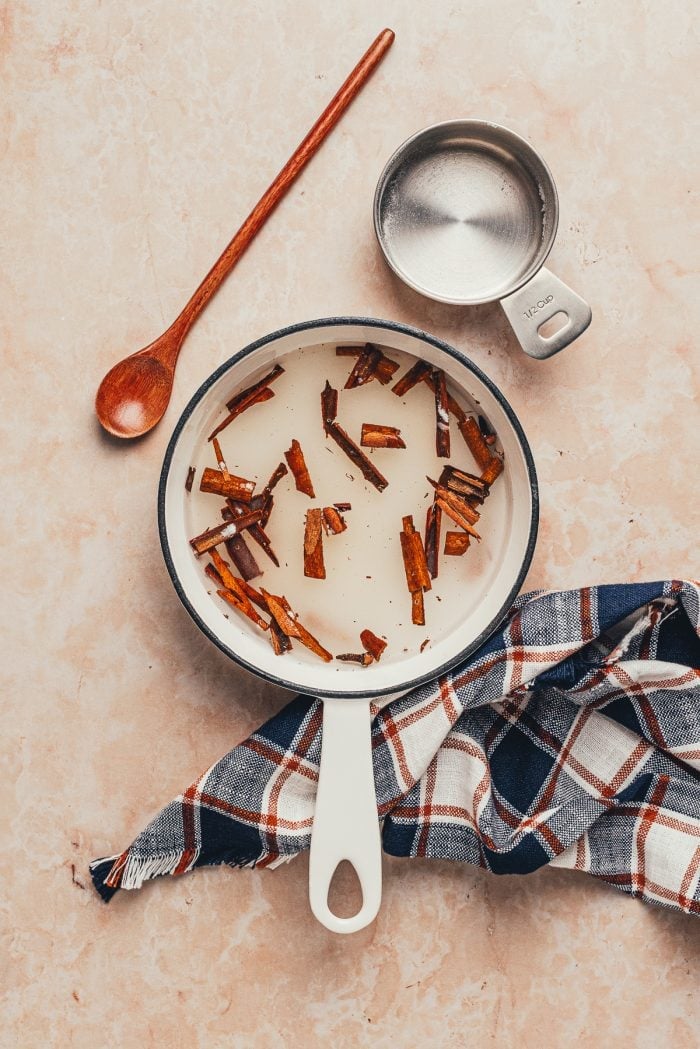 A saucepan with cinnamon sticks and water in it.