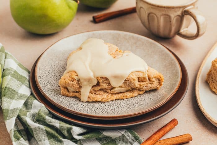 A cinnamon apple scone on a plate with a plaid green towel.