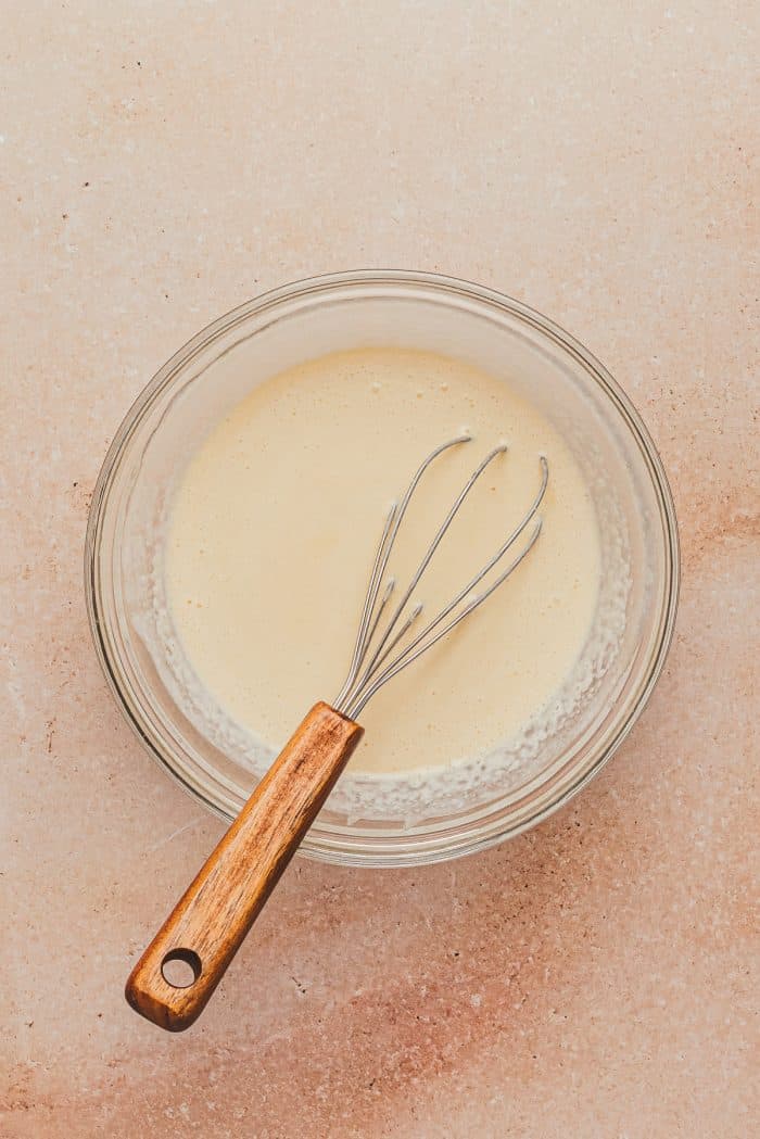 A glass mixing bowl with the cream, egg, and vanilla. 