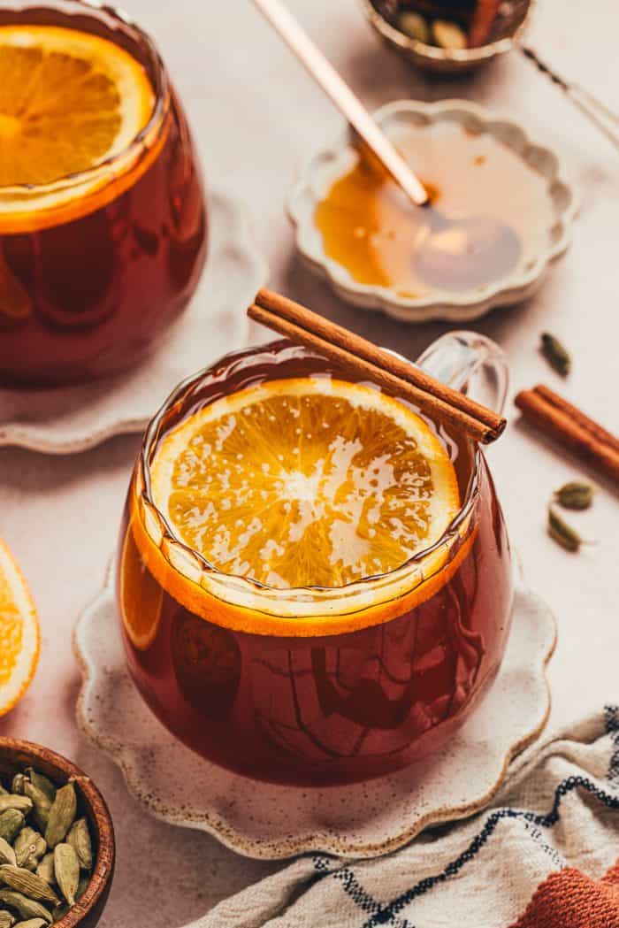 A glass mug filled with chai vanilla bean hot toddy and garnished with orange slices.