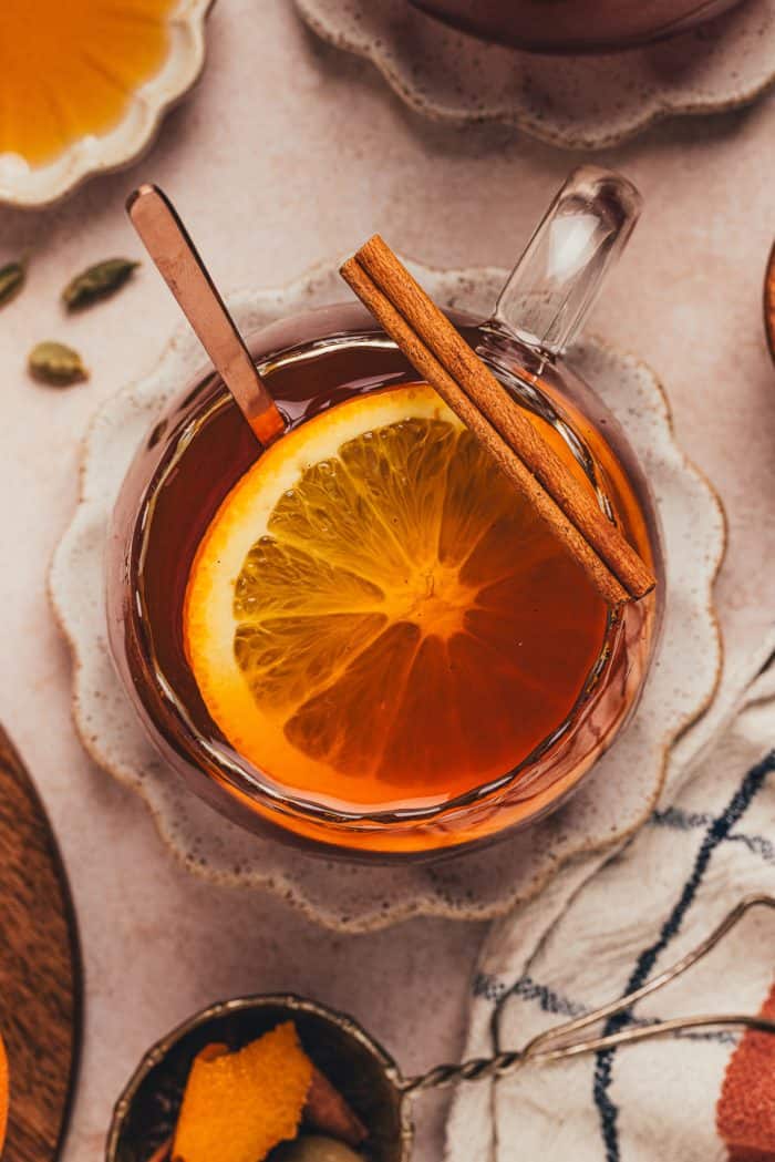 A glass mug filled with chai vanilla bean hot toddy and garnished with orange slices.