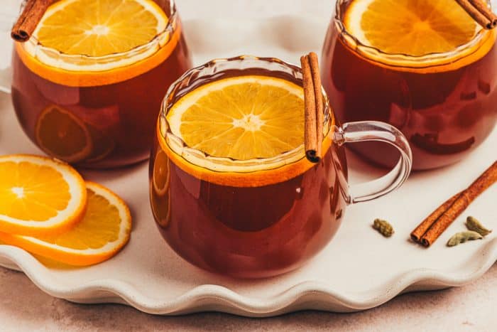 A set of 3 chai hot toddies garnished with orange slices.