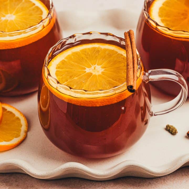 A set of 3 chai hot toddies garnished with orange slices.