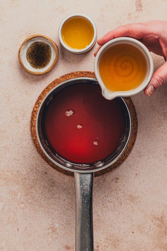 Orange juice being added to the saucepan with the chai hot toddy mixture. 