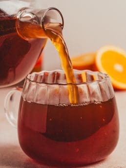 The chai hot toddy mixture being poured into a glass mug.